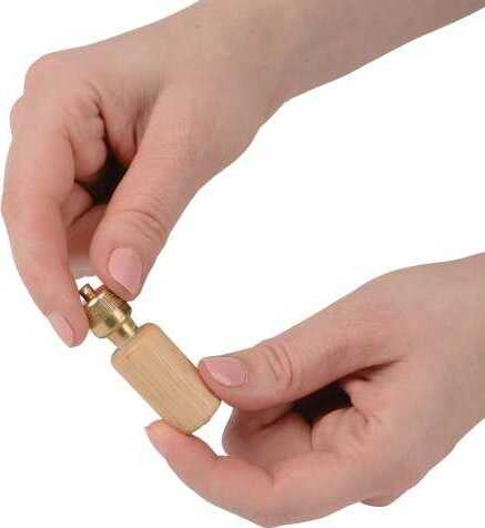 A person holds a Bird Call DIY kit by U.S. Toy in their hands. The kit features a wooden body with a brass end that facilitates sound production, ideal for bird enthusiasts and outdoor activities.