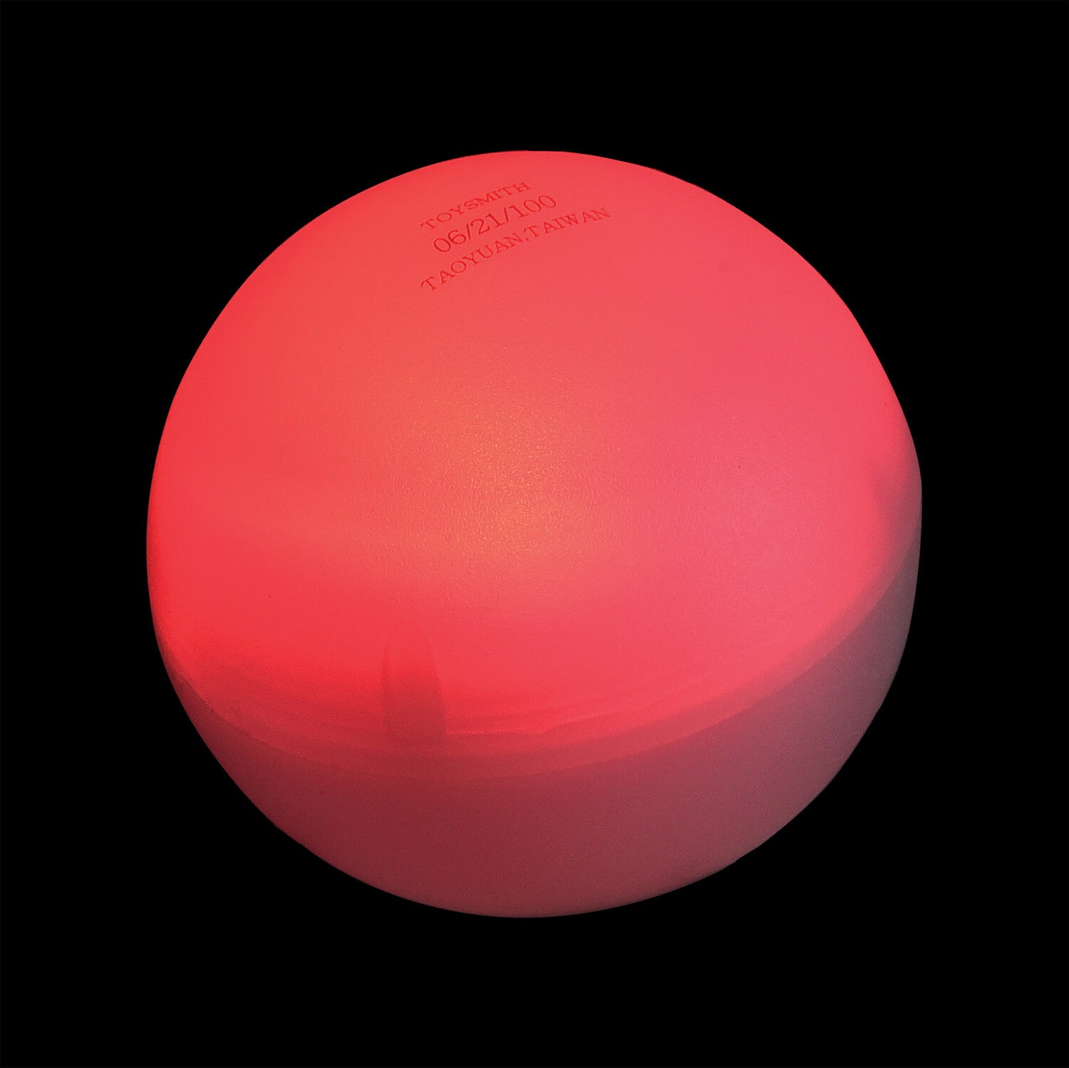 A vibrant, glowing red ball with a smooth texture, designed by U.S. Toy. The ball has a matte finish and features minimal engravings on top, providing a sensory experience that is perfect for fidgeting or stress relief. The image features the ball against a black background, enhancing its luminous appearance.