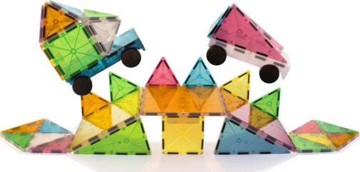 The Grand Prix Magna Tiles set consists of 50 colorful, translucent geometric pieces in various shapes including triangles, squares, and rectangles. The tiles are arranged to create a playful scene featuring two toy cars and a vibrant structure made from the pieces, showcasing the endless possibilities of creativity and construction.
