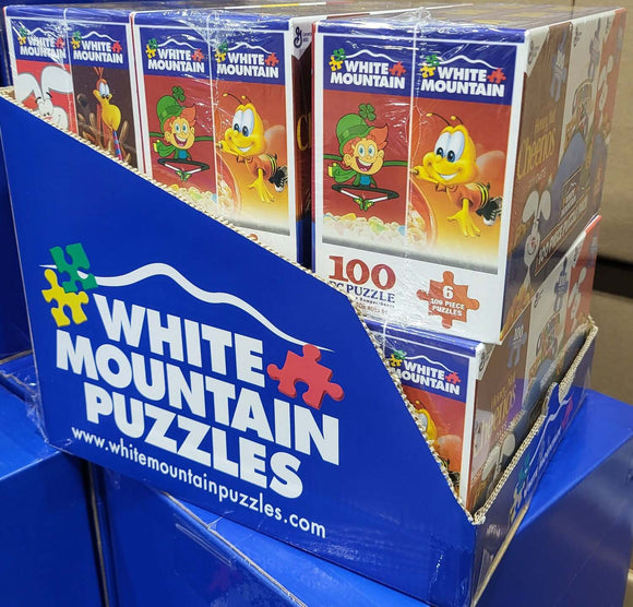 A display of Mini Cereal Boxes 6 Pack jigsaw puzzles made by White Mountain Puzzles, featuring colorful designs of cartoon characters. Each box includes 100 puzzle pieces, perfect for family fun and entertainment.