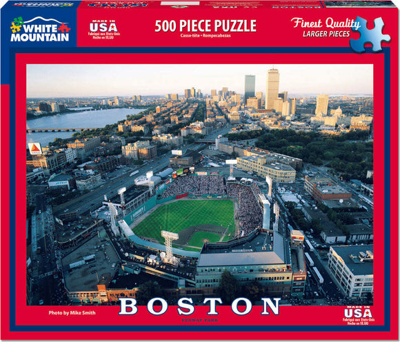 A vibrant jigsaw puzzle featuring an aerial view of Boston's Fenway Park during a game. The image showcases the historic ballpark surrounded by the Boston skyline and the Charles River, highlighting the energetic atmosphere of baseball season. The puzzle consists of 500 larger pieces, designed for easier handling and assembly, perfect for both puzzle enthusiasts and casual hobbyists.