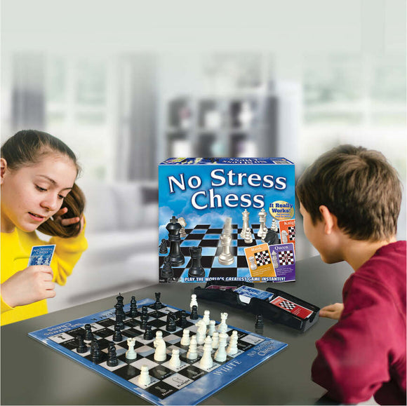 A girl and a boy sitting at a table playing No Stress Chess by Winning Moves. The game box is visible, featuring a vivid design. The chessboard is set up with black and white pieces, and the boy appears focused on the game, while the girl is holding a card and smiling. The background shows a cozy living room setting.