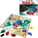 Risk 1980's Edition board game by Winning Moves. The image shows the game board featuring a colorful world map with various territories, along with an assortment of game pieces in different colors (red, yellow, green, black) and dice. The box is visible in the background, displaying iconic game branding.