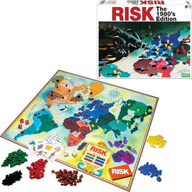 Risk 1980's Edition board game by Winning Moves. The image shows the game board featuring a colorful world map with various territories, along with an assortment of game pieces in different colors (red, yellow, green, black) and dice. The box is visible in the background, displaying iconic game branding.