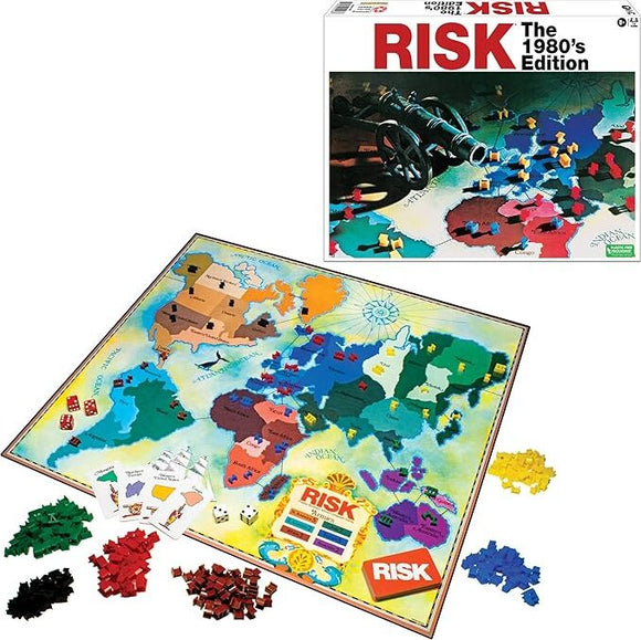 Risk 1980's Edition board game by Winning Moves. The image shows the game board featuring a colorful world map with various territories, along with an assortment of game pieces in different colors (red, yellow, green, black) and dice. The box is visible in the background, displaying iconic game branding.