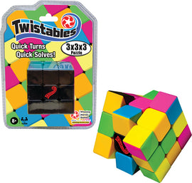 The Twistables 3x3x3 puzzle by Winning Moves features a vibrant design with colorful squares in pink, yellow, green, and blue. The puzzle is partially twisted to display its mechanical function, emphasizing quick turns and easy solving. Packaging is visible, highlighting the product name and features, along with a warning for appropriate age.