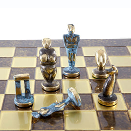 A Cycladic Art Chess Set by Manopoulous featuring unique figurine chess pieces inspired by ancient Greek culture. The chessboard has a glossy finish with contrasting tiles, showcasing the artistic deign of the characters.