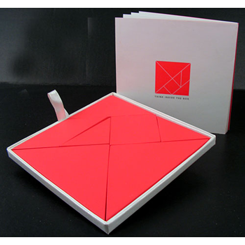 Think Inside the Box tangram set by IPP featuring a mechanical puzzle with bright red geometric shapes neatly arranged in a white box. The set includes a booklet for instructions and ideas. Perfect for enhancing problem-solving skills and creativity.