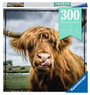 Ravensburger Jigsaw Puzzle titled 'Puzzle Moments: Highland Cattle' featuring a close-up image of a Highland cow with long, shaggy fur and large horns, licking its nose. The puzzle contains 300 pieces and emphasizes a relaxing and enjoyable experience.