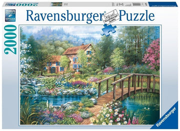 The 'Shades of Summer' jigsaw puzzle by Ravensburger features a vibrant, picturesque scene of a charming house surrounded by a lush garden filled with colorful flowers and a serene stream with a wooden bridge. The artwork is designed with intricate details and rich colors, capturing the essence of summer tranquility. This 2000-piece jigsaw puzzle is perfect for puzzle enthusiasts and nature lovers.