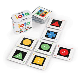 A colorful card game called IOTA by Gamewright. The game features various cards with geometric shapes and colors, arranged in a fun layout, with a round tin container in the background. Each card displays distinct shapes like triangles, circles, squares, and rectangles, inviting players to engage in strategic gameplay.