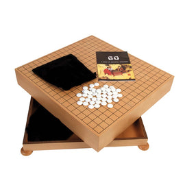 The Go Chest with Stones from John N. Hansen Co. Inc. features a wooden game board with a grid, white stones arranged on the surface, and a soft black pouch. The set includes a booklet titled 'GO: A Game of Oriental Strategy' and has a drawer for storage.