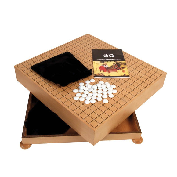 The Go Chest with Stones from John N. Hansen Co. Inc. features a wooden game board with a grid, white stones arranged on the surface, and a soft black pouch. The set includes a booklet titled 'GO: A Game of Oriental Strategy' and has a drawer for storage.
