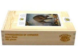 Wooden jigsaw puzzle titled 'Consequences of Hypnosis' by Kevin Sloan. The puzzle features a decorative wooden box with the title and details engraved. It includes 282 pieces and showcases a whimsical image related to hypnosis.