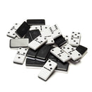 A collection of black and white dominoes scattered on a surface, showcasing various dot patterns. The dominoes feature a classic design, ideal for family games and gatherings.