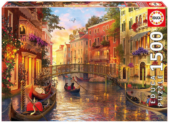 The jigsaw puzzle titled 'Sunset in Venice' by Educa, featuring a picturesque scene of gondolas on a serene canal in Venice during sunset. The vibrant colors highlight charming buildings with balconies adorned with flowers, a decorative bridge, and clear blue skies, creating a captivating atmosphere perfect for puzzle enthusiasts.