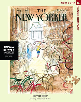 A colorful 1000-piece jigsaw puzzle titled 'Bicycle Shop' by New York Puzzle Company, featuring a whimsical illustration of a bicycle shop filled with various bicycles, tools, and vibrant colors. The design reflects the cover art by Jean-Jacques Sempé from The New Yorker dated August 1, 1988.