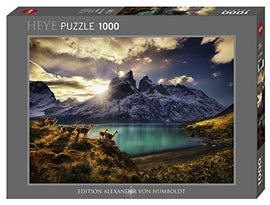 A 1000-piece jigsaw puzzle titled 'Guanacos' by Heye, featuring a stunning landscape of mountains and a lake with a group of guanacos in the foreground, set during a dramatic sunset. The box displays the intricate artwork and details of the scene.