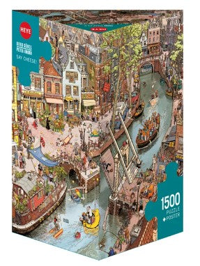 A vibrant, colorful jigsaw puzzle box titled 'Say Cheese!' by Heye, featuring a detailed illustration of a lively canal scene with boats, historic buildings, and people enjoying a sunny day. The box contains 1500 puzzle pieces and includes a poster of the illustration.