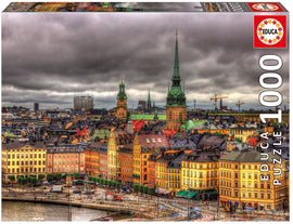 Educa jigsaw puzzle titled 'Views of Stockholm, Sweden' featuring a colorful and detailed aerial view of Stockholm’s architecture, with towers and rooftops under a cloudy sky. The puzzle has 1000 pieces and is designed for adults and older children. Its vibrant imagery showcases the historical buildings and modern elements of the cityscape.
