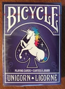 Bicycle Unicorn Playing Cards featuring a whimsical unicorn illustration set against a purple background. The card box displays vibrant colors and elegant typography, perfect for both casual and serious card players who love unique designs.
