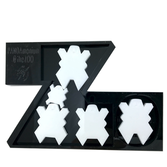 A mechanical puzzle featuring a whimsical design with several panda-shaped pieces arranged within a stylized letter 'Z'. The black base is engraved with 'PANDAmonium @ the ZOO', showcasing a playful and interactive way to engage with the San Diego Zoo theme.