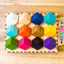 Chroma Cube by Project Genius, a vibrant mechanical puzzle featuring 12 colored cubes in various shapes arranged on a wooden base. Each cube is crafted in bright colors including white, orange, green, purple, and blue, designed to challenge and engage while offering an aesthetically pleasing experience.