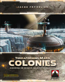 Front cover of the board game 'Terraforming Mars: Colonies' by Stronghold Games. The artwork features a futuristic colony on an icy landscape, highlighting a domed structure with a cryogenics label and technological towers, all set against a backdrop of a distant planet and starry sky. The title 'Terraforming Mars: Colonies' and the subtitle 'Harvesting the Riches of the Outer Solar System' are prominently displayed.