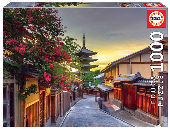 Educa jigsaw puzzle featuring a scenic view of YASAKA PAGODA in Kyoto, Japan. The image captures traditional Japanese architecture, flowering trees, and a tranquil street at sunset, offering a serene and immersive experience for puzzle enthusiasts.