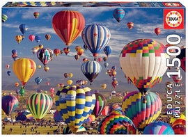 A vibrant jigsaw puzzle box featuring a stunning scene of numerous colorful hot air balloons soaring against a clear blue sky, with mountains in the background. The puzzle contains 1500 pieces and is produced by Educa.