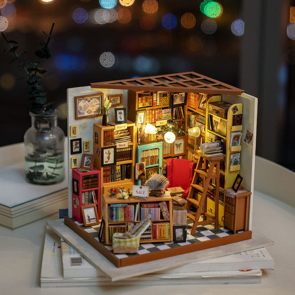 Sam's Study Model Kit by Robotime, a detailed DIY miniature scene featuring a cozy study with bookshelves filled with colorful books, a red armchair, a wooden ladder, and warm lighting, perfect for creative building and design enthusiasts.