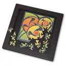 Curiosi Puzzle Tray Medium, a jigsaw puzzle featuring an artistic design with vibrant colors. The tray displays an incomplete puzzle showing circular shapes in orange, yellow, and green, with some pieces scattered around the edges, set against a black background.