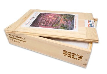 The Bookkeeper jigsaw puzzle by Nicole Gustafsson, produced by Artifact Wooden Puzzles. The image shows a beautifully crafted wooden box containing the puzzle with a colorful artwork of a whimsical setting on the cover. The packaging features the product's title and brand laser-etched onto the wood, showcasing its quality and craftsmanship.