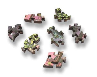 A close-up view of intricately designed wooden jigsaw puzzle pieces from 'The Bookkeeper' by Nicole Gustafsson. The pieces feature colorful floral patterns and are handcrafted by Artifact Wooden Puzzles, showcasing the artistic detail and craftsmanship.