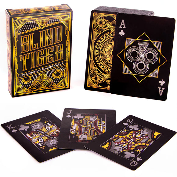 Blind Tiger Prohibition playing cards by Brybelly displayed in a stylish box. The deck features intricate designs in black and gold, showcasing unique face cards, including King, Queen, and Jack of Spades. A distinctive Ace of Spades card is also visible. Perfect for card game enthusiasts and collectors.