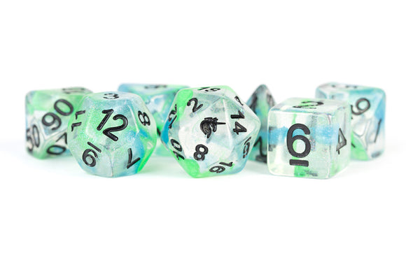 A close-up view of a set of Unicorn Resin Polyhedral Dice arranged artistically. The dice feature a clear resin base with a swirling mix of colors including green and blue, accented by bold black numbers. Perfect for tabletop role-playing games, these unique and vibrant dice add a magical touch to your game nights.