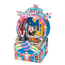 A colorful DIY music box kit featuring an amusement park theme. The design includes a circus setup with vibrant colors, a monkey lifting weights, a rabbit in a box, and decorative elements like stars, balloons, and clowns. Perfect for hands-on creativity and music enthusiasts.
