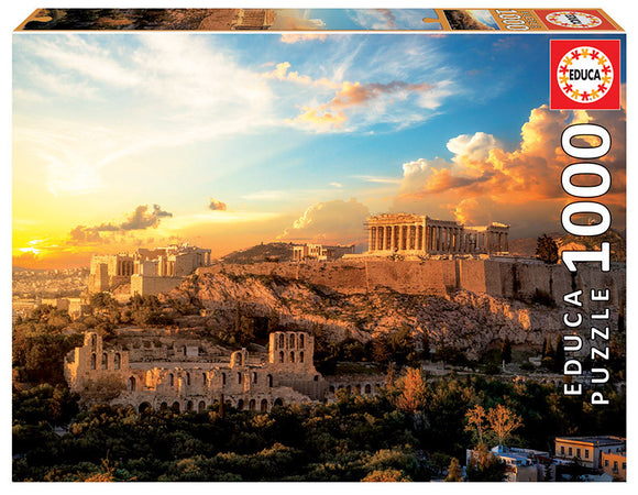 A box displaying the ACROPOLIS OF ATHENS jigsaw puzzle by Educa. The image showcases the iconic Acropolis under a vibrant sunset sky, surrounded by lush greenery and historical ruins. The puzzle contains 1000 pieces, offering a beautiful and engaging way to explore ancient Greek architecture and scenery.