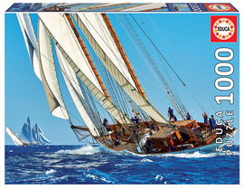 Educa YACHT jigsaw puzzle featuring a vibrant and detailed image of a sailing ship in motion on the ocean, with crew members on deck and other sailboats in the background. This 1000-piece puzzle offers an engaging challenge for puzzle enthusiasts and is perfect for coastal or sailing theme lovers.