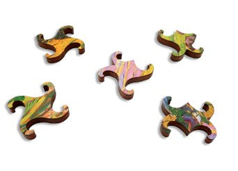 Colorful jigsaw puzzle pieces from the Layers of Afternoon by Erin Hansen, made by Artifact Wooden Puzzles. The pieces feature vibrant swirls of pink, green, and yellow on a wooden finish, showcasing intricate shapes.