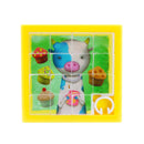 A colorful Tiny Tile Puzzle by House of Marbles featuring a cheerful cartoon cow holding a jar and surrounded by cupcakes. The puzzle consists of small, square tiles arranged in a grid, with a vibrant yellow frame.