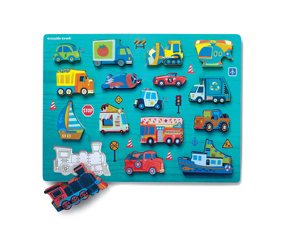 A colorful wooden jigsaw puzzle featuring various vehicles including cars, trucks, boats, a train, and construction equipment, arranged on a bright turquoise background. The puzzle pieces are intricately designed with playful illustrations and icons related to transportation.