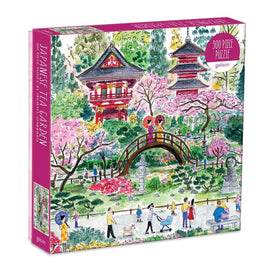 A beautifully illustrated box for the Japanese Tea Garden jigsaw puzzle by Galison. The artwork depicts a serene garden scene featuring colorful cherry blossoms, traditional Japanese architecture, a charming bridge, and people enjoying the scenery. It includes vibrant colors and intricate details that invite puzzle enthusiasts to engage in this 300-piece challenge.