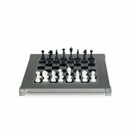 A detailed view of a Staunton-style chess set made of metal. The set features elegantly designed black and white pieces arranged on a classic black-and-white checkered board with ornate silver legs.