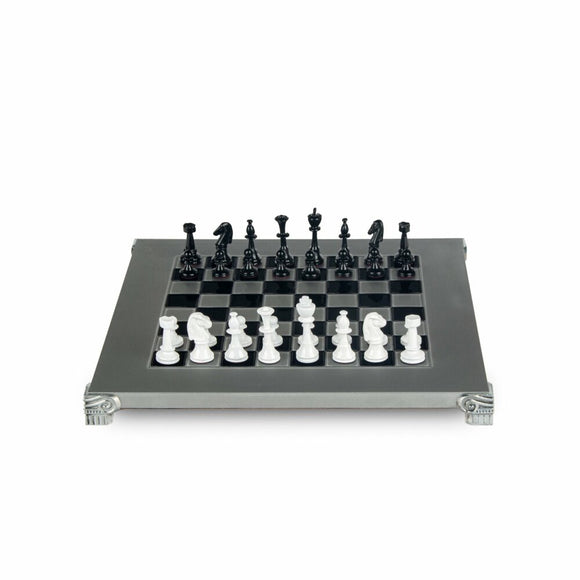 A detailed view of a Staunton-style chess set made of metal. The set features elegantly designed black and white pieces arranged on a classic black-and-white checkered board with ornate silver legs.
