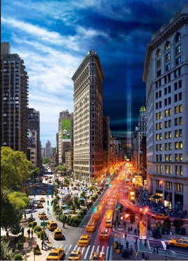 A beautifully illustrated jigsaw puzzle featuring a dynamic view of the iconic Flatiron Building in New York City, captured in a day-to-night transition. The scene showcases bustling streets filled with yellow taxis, pedestrians, and vibrant city life, framed by dramatic skies. Perfect for puzzle enthusiasts and lovers of urban landscapes.