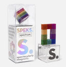 The Speks Spectrum is a colorful DIY magnet kit featuring vibrant rainbow-colored magnetic balls displayed in a clear box. One side showcases the assembled magnetic structure shaped as a letter 'S', highlighting its creative potential for building and exploring magnetic artistry. The packaging emphasizes its attributes: mashable, smashable, buildable, and colorful fun.