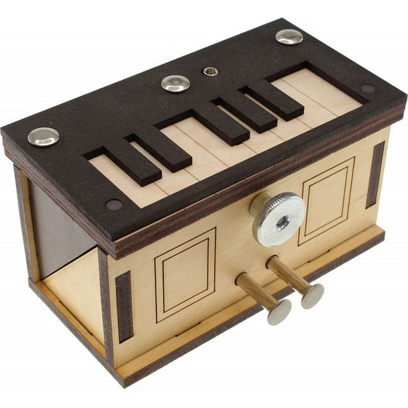 A detailed view of a Piano Box mechanical puzzle designed by Jean-Claude Constantin. The box features a minimalist wooden design with a piano keyboard on the top and brass knobs on the side, demonstrating intricate craftsmanship and functionality as a mechanical puzzle.