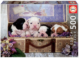 Educa 500-piece jigsaw puzzle featuring a charming image of four adorable puppies snuggled together in an antique suitcase, surrounded by flowers. This puzzle offers both fun and a delightful visual experience for dog lovers.