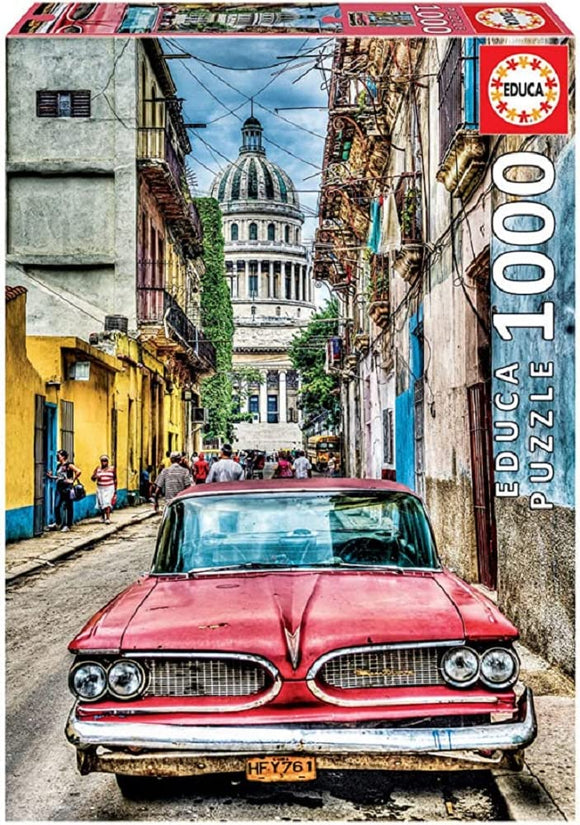Educa Vintage Car in Old Havana jigsaw puzzle featuring a classic red car parked on a narrow street flanked by colorful buildings, with the Havana skyline in the background.